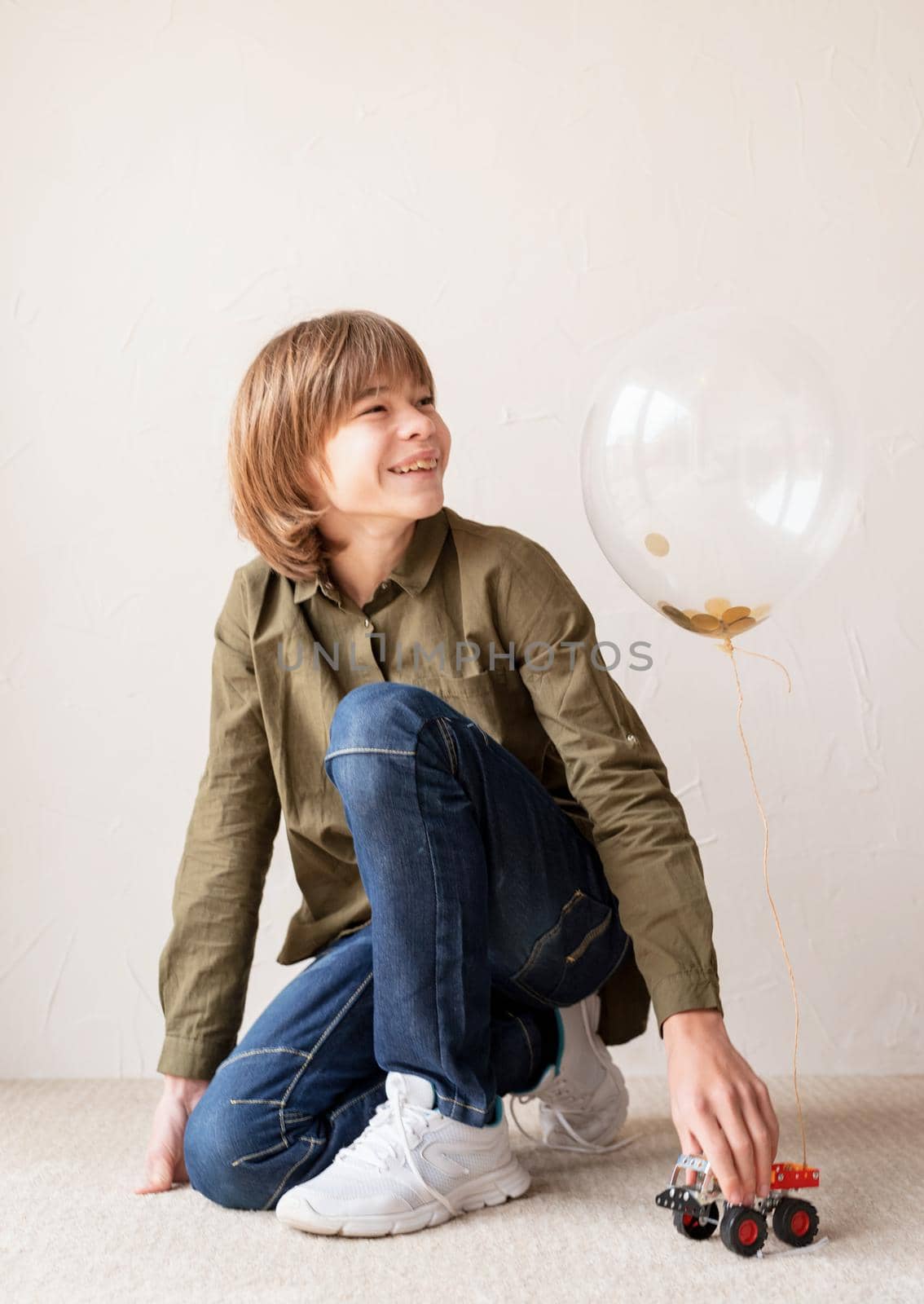 Happy boy playing with a car with helium balloon