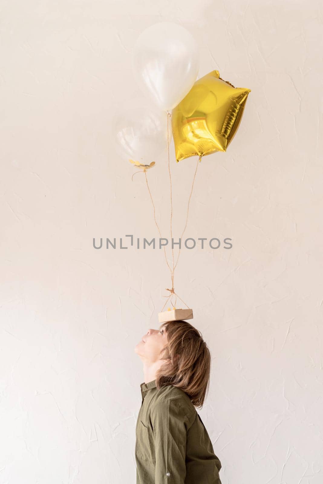 funny boy playing with helium balloons, holding them on his head by Desperada