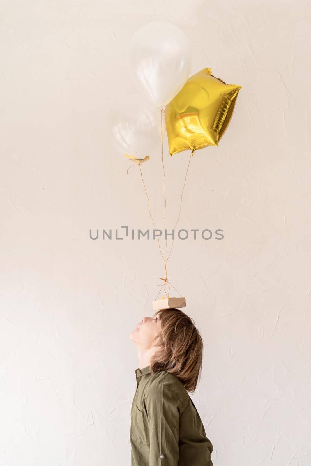 funny young boy playing with helium balloons, holding them on his head