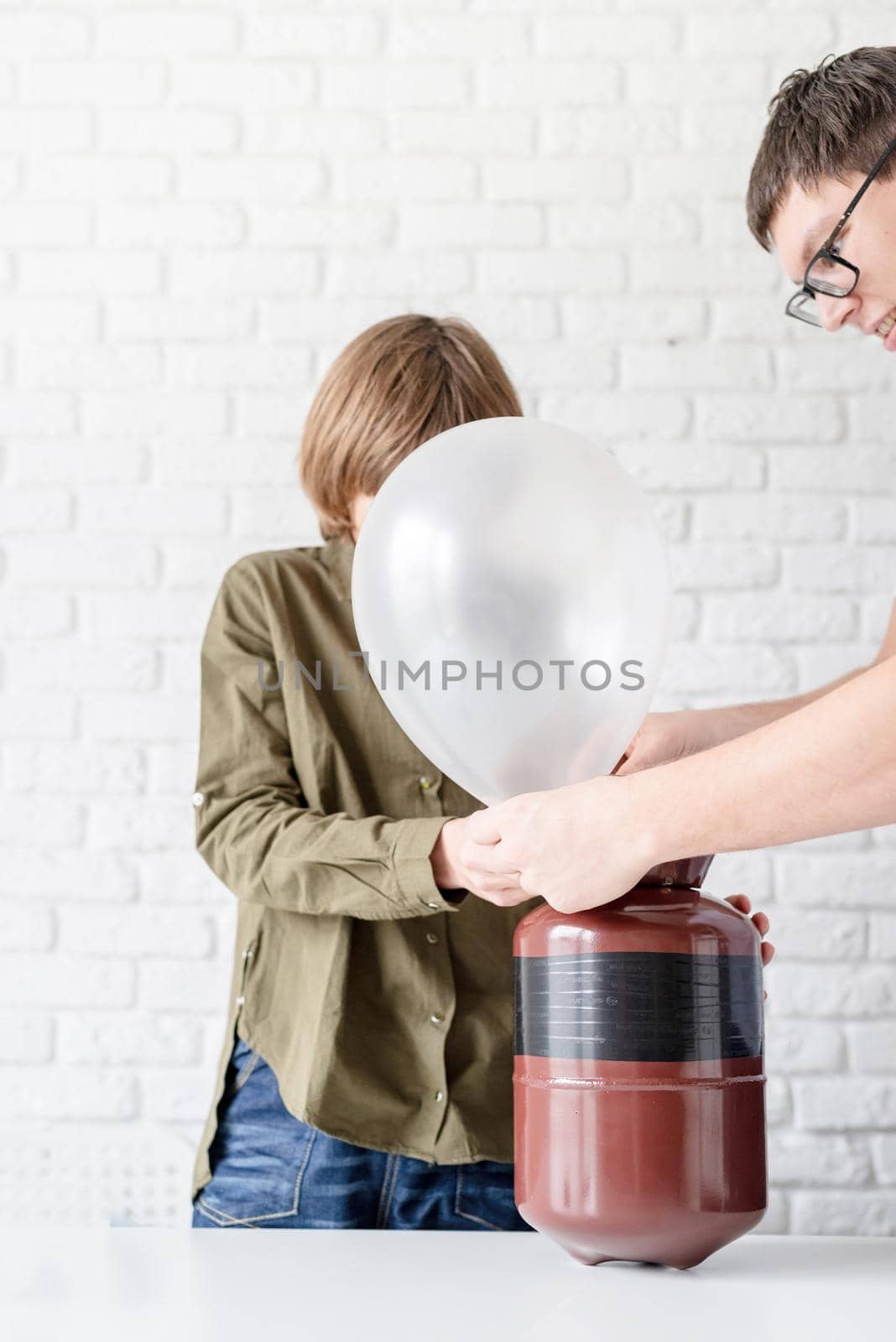 boy blowing up a balloon with helium by Desperada