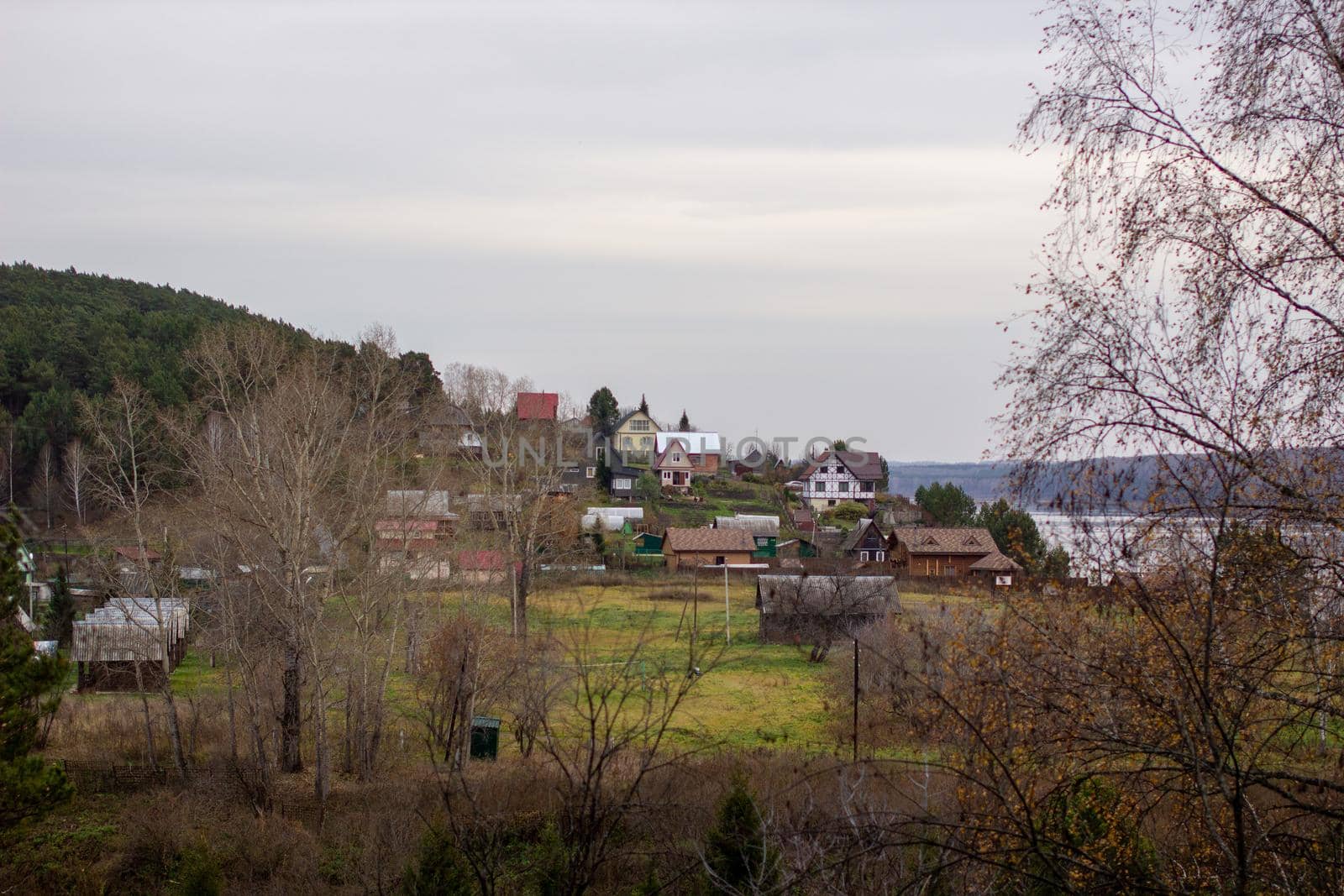 Houses along a beautiful, wide river in the middle of the forest. Calm and quiet place with autumn colors. In the middle of the river island. View from the top to the distance