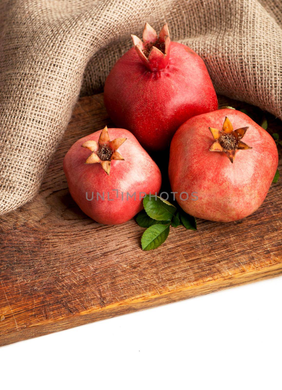 ripe pomegranate with leaves on a wooden board by aprilphoto
