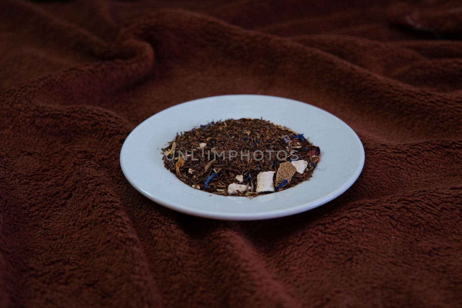 White plate with natural tea on a brown background by xavier_photo