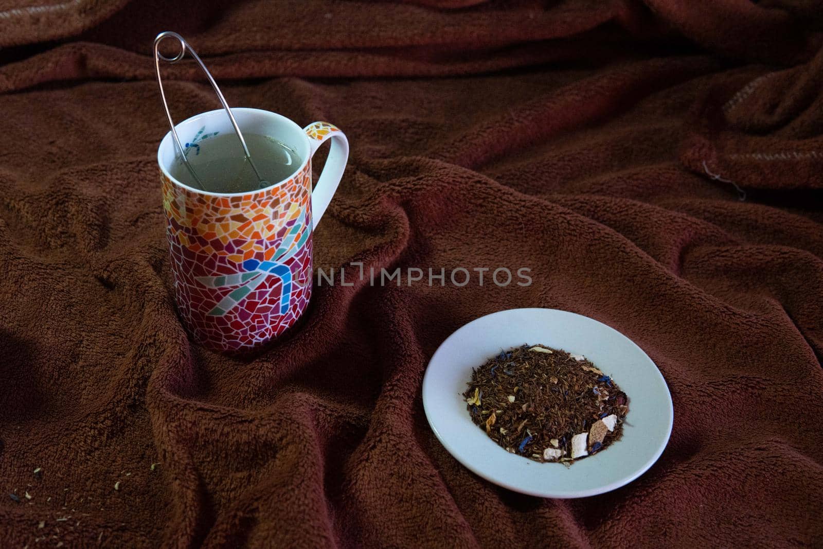 Making a tea in a colorful cup and a white saucer with natural tea by xavier_photo