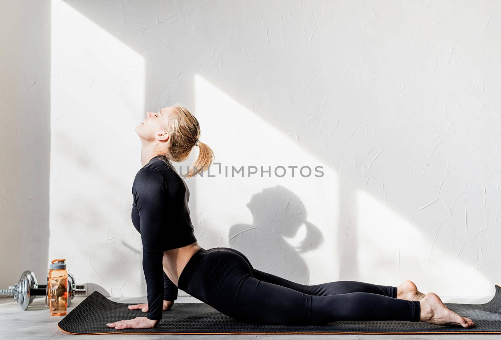 Young athletic woman working out or doing yoga stretching at home by Desperada
