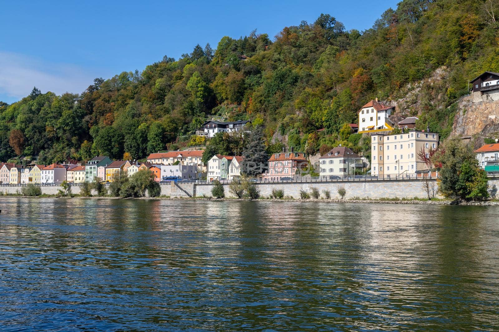 View at a house front in Passau on the Danube river in autumn with multicolored trees on a hill