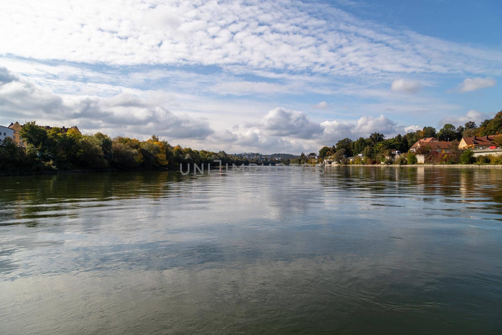 View at Danube shore in Passau during a ship excursion in autumn with multicolored trees 