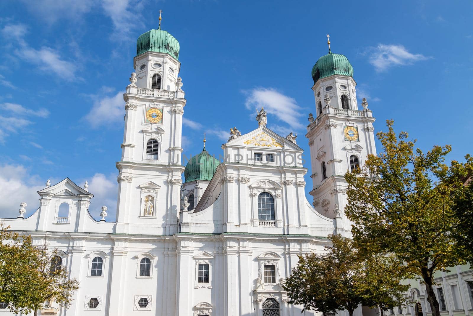 The front of St. Stephen's Cathedral (Dom St. Stephan) in Passau, Bavaria, Germany in autumn with multicolored trees in foregound