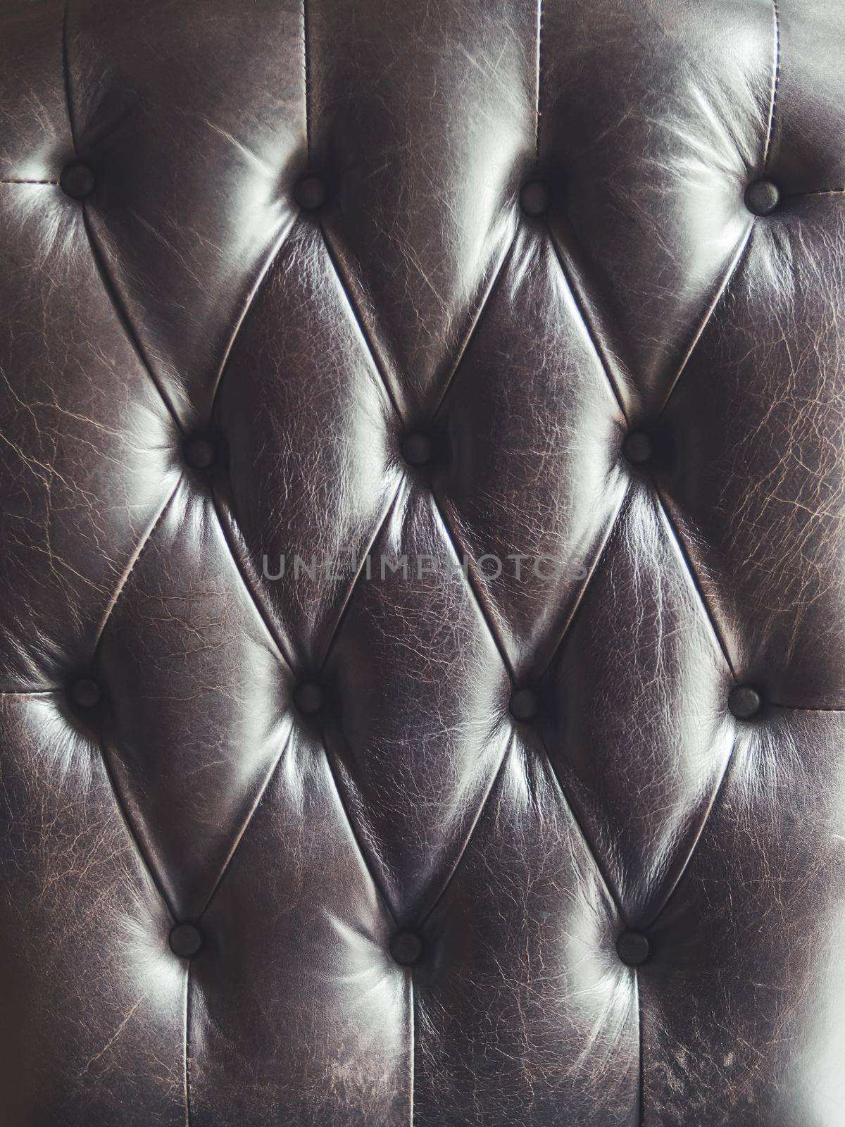Leather sofa. Capitone or Chesterfield technique of furniture upholstery. Dark elegant furniture for lofts. Fabric background. Natural textured backdrop.