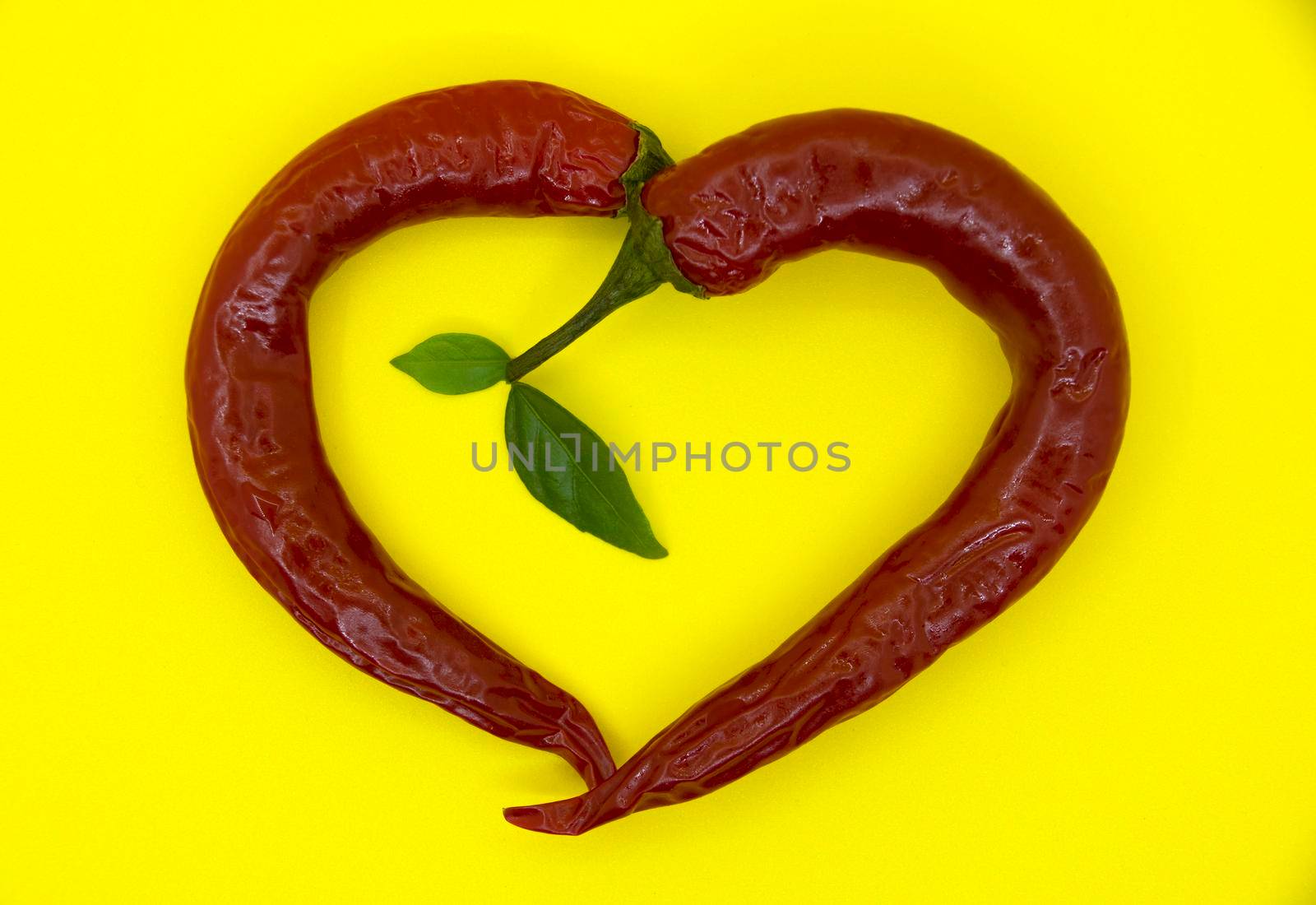 Hot heart of hot red pepper on a yellow background.