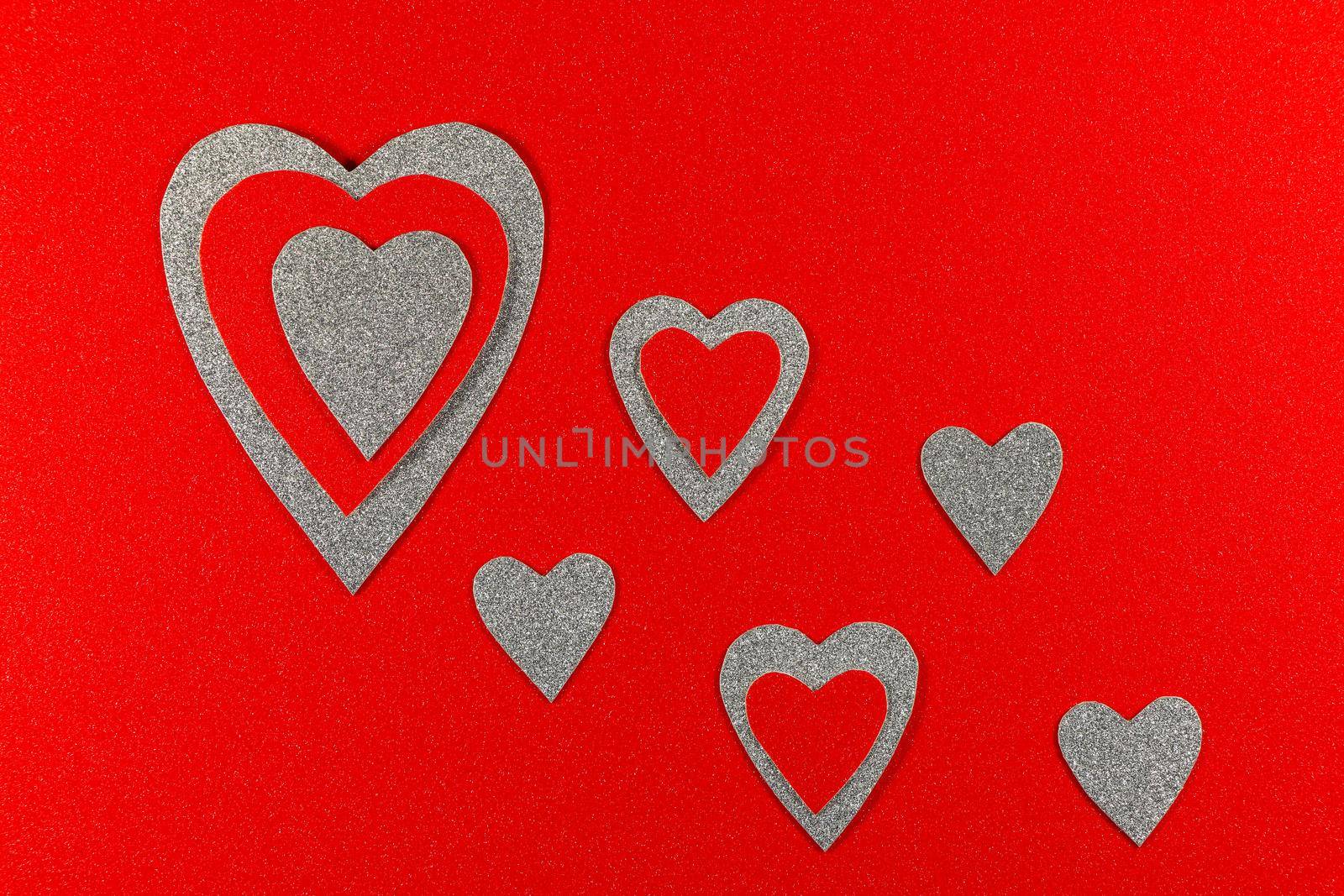 Saint Valentine's day love themed flat-lay design red and silver hearts on textured red background