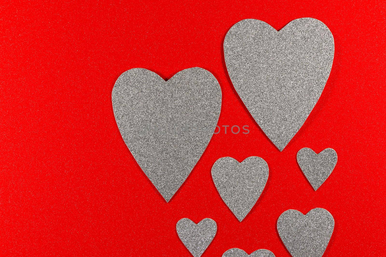 Saint Valentine's day love themed flat-lay design silver hearts rising on textured red background