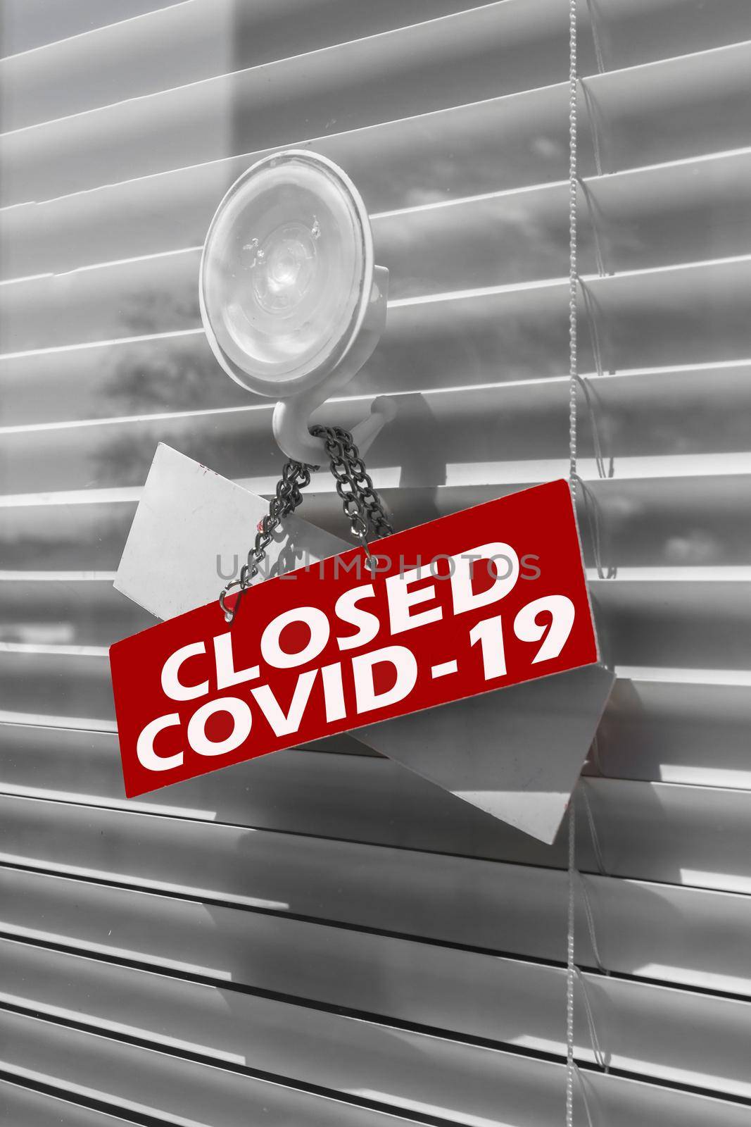 Close-up on a red closed sign in the window of a shop/office displaying the message "Closed due to Covid-19".