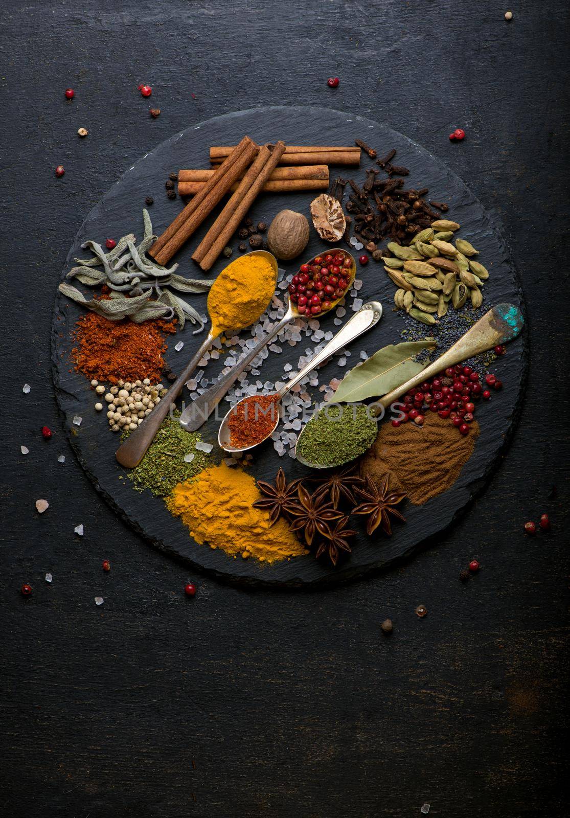 Powder spices on spoons in black wooden table background by aprilphoto