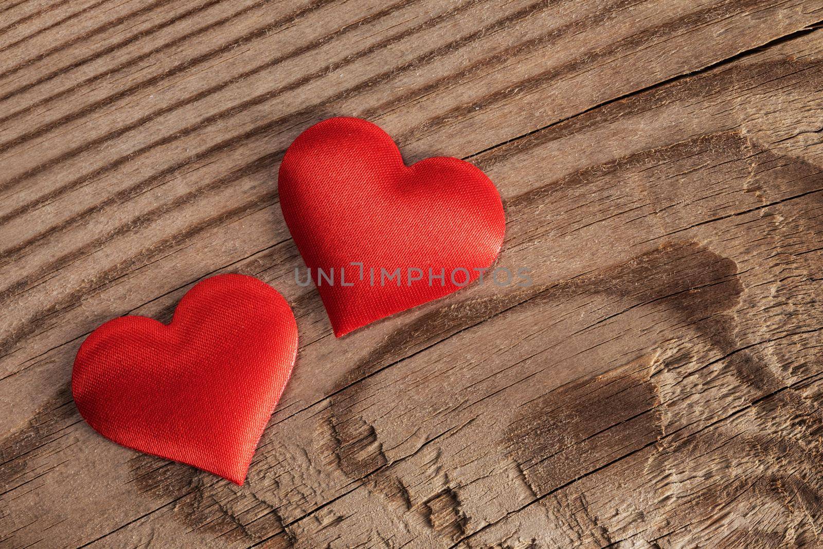 Valentine's day two red silk hearts on wooden background, love concept