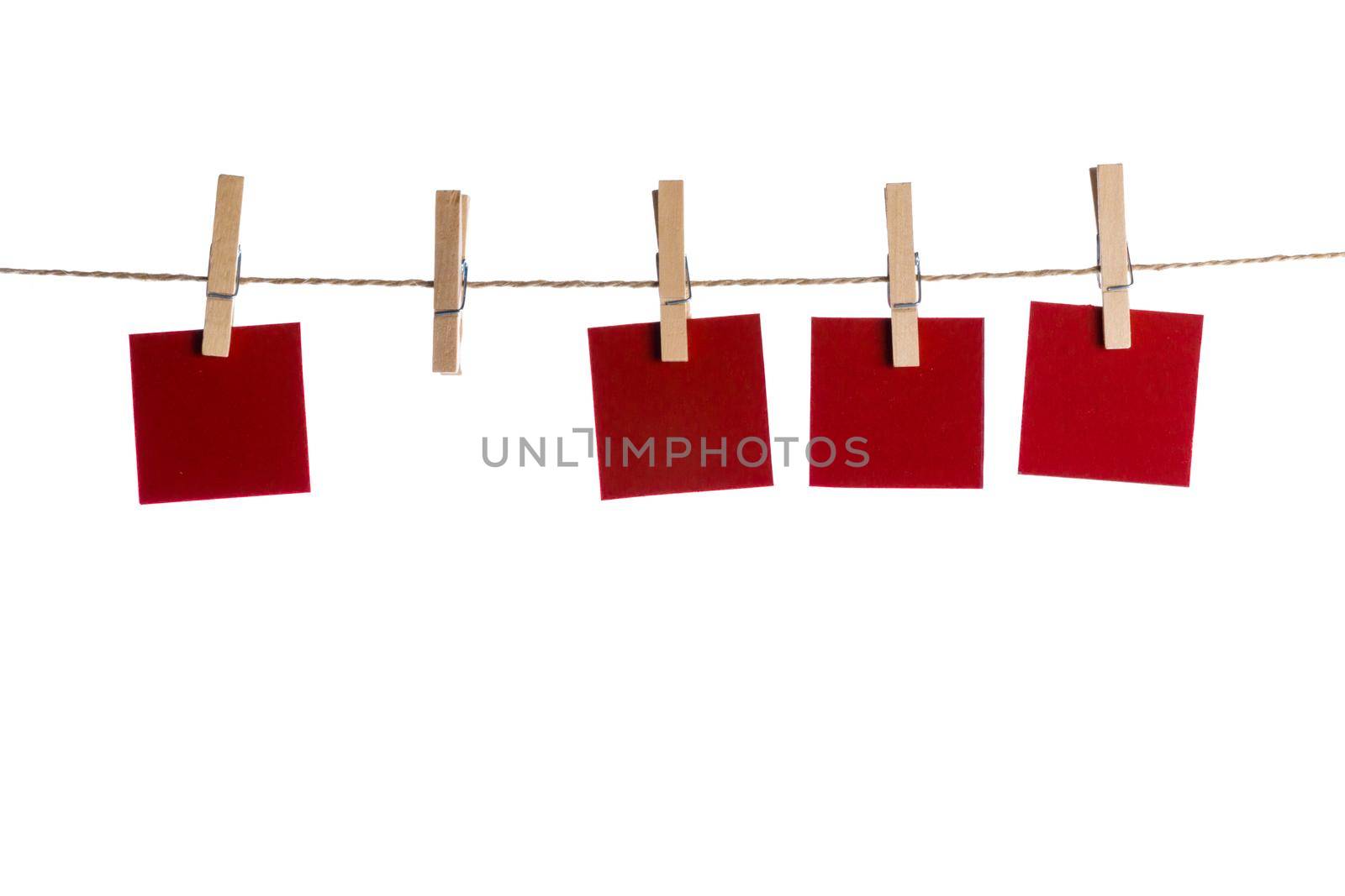 Set of four red blank paper notes held on a string with clothespins isolated on white background