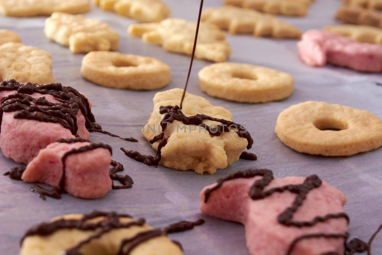 Pouring chocolate on just baked christmas cookies