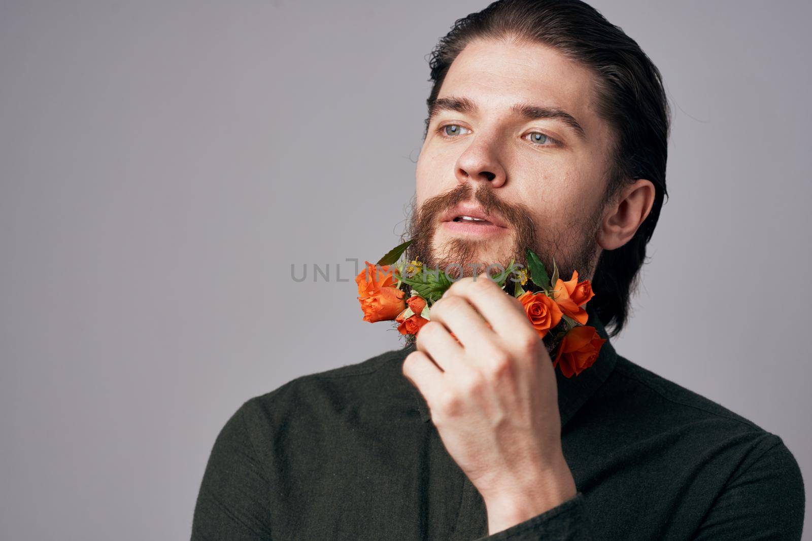 Cute elegant man in a black shirt flowers in a beard decoration romance gray background. High quality photo