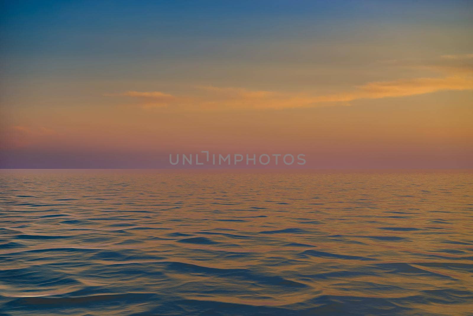 bright sunset over the blue sea with shimmering different colors in the clouds