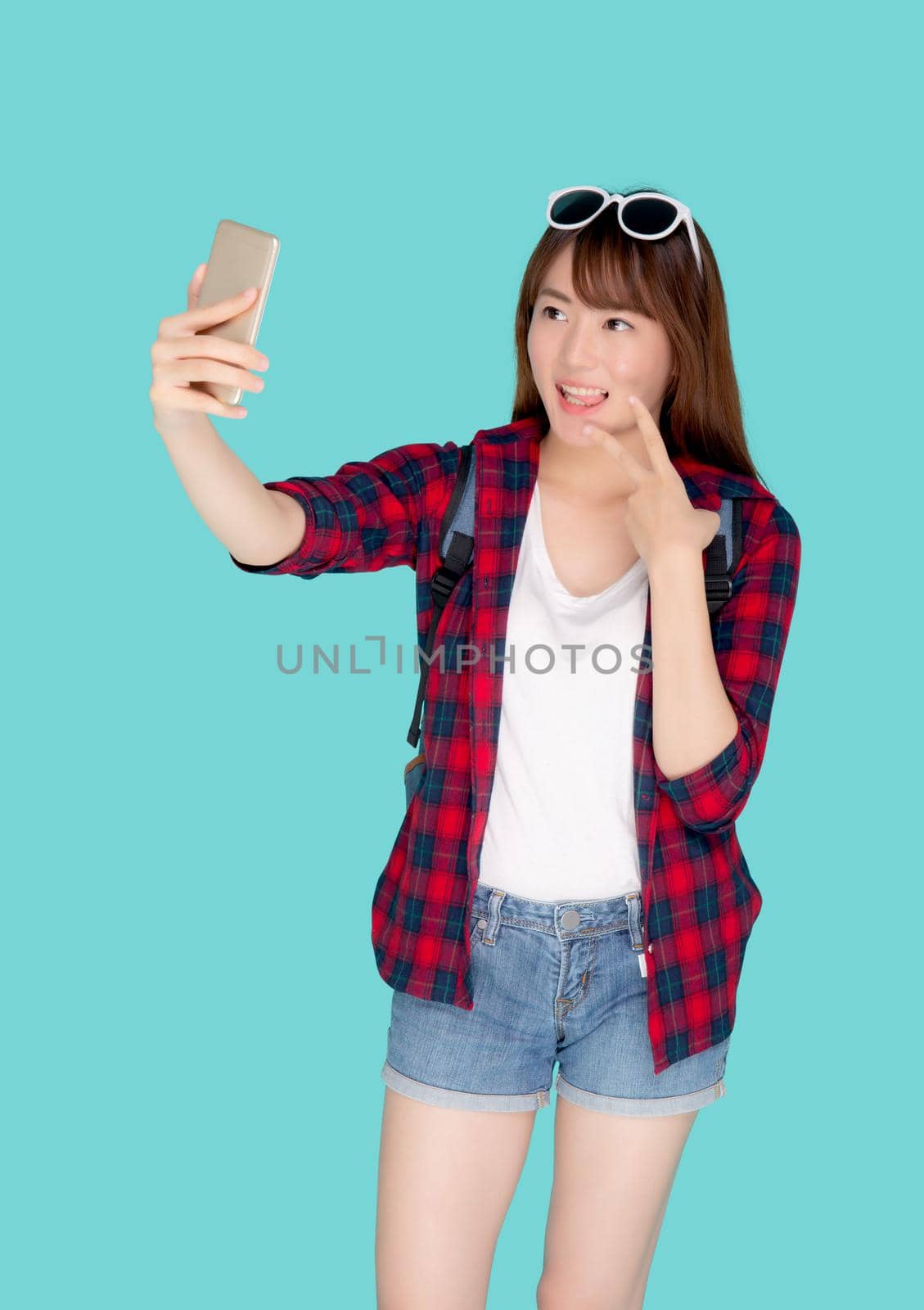 Beautiful portrait young asian woman cheerful smiling and take selfie on smart mobile phone, beauty girl wear travel summer enjoy and fun in vacation isolated on blue background, holiday concept. by nnudoo
