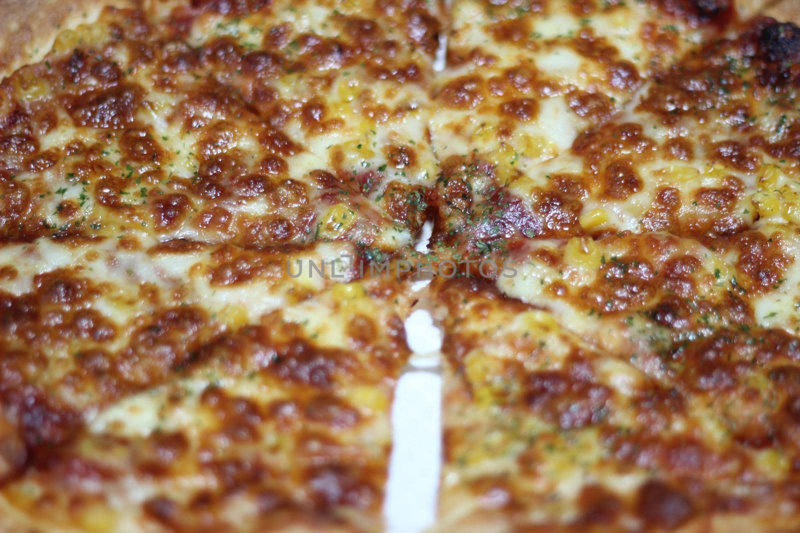 Pizza made with tasty pizza dough, cheese, tomatoes, and green olives. Closeup view of cheese pizza served for dinner
