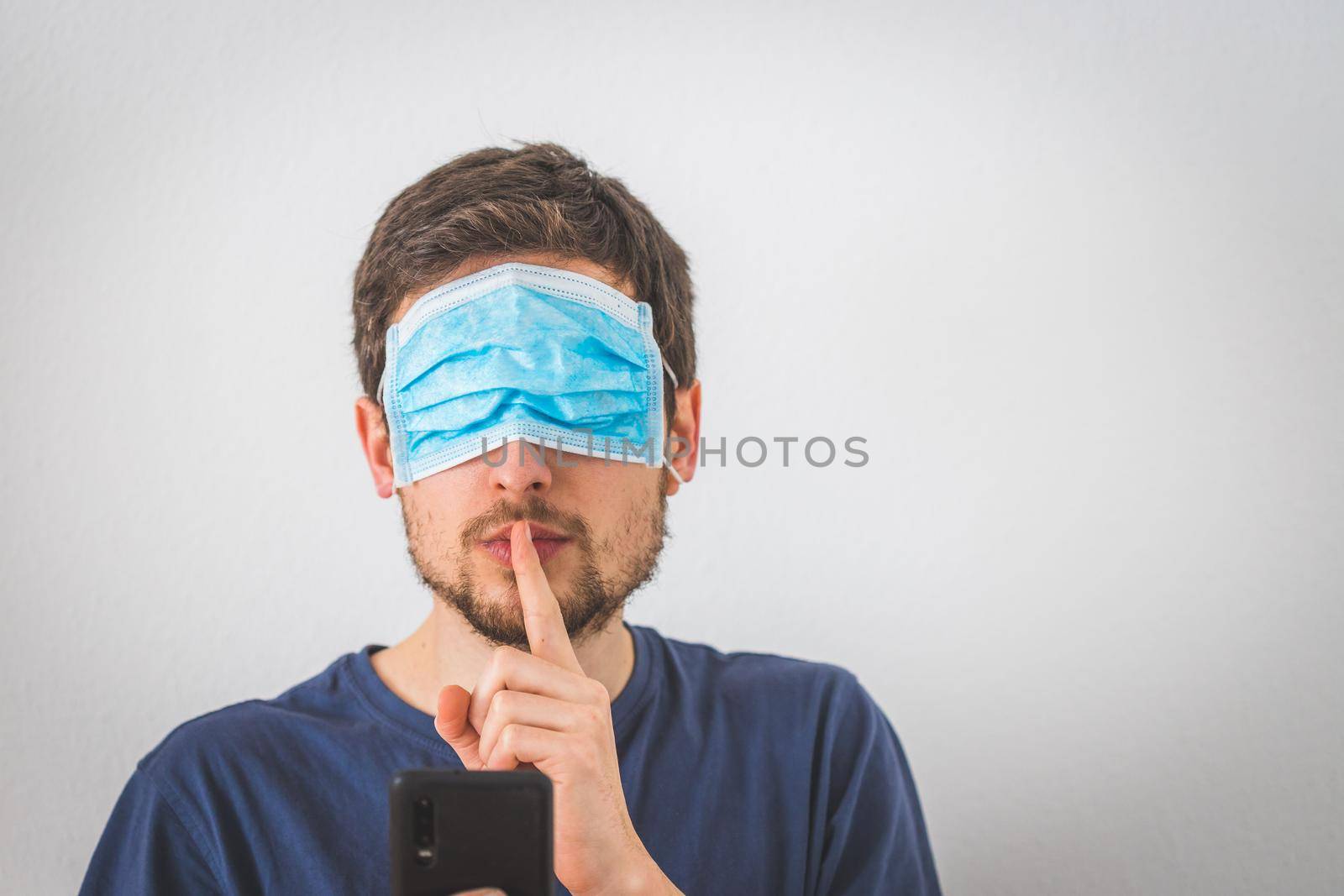 Young angry man with face mask over the eyes is doing a psst! gesture