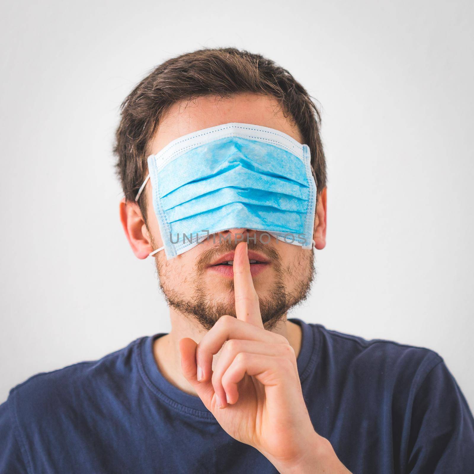 Young angry man with face mask over the eyes is doing a psst! gesture