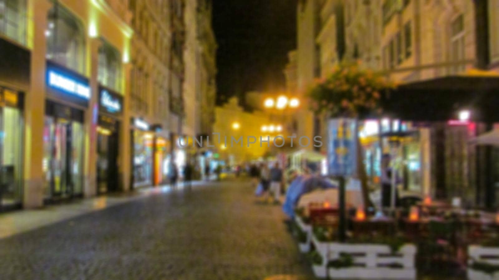 Evening city landscape, city street with lights and passers-by. Creative background with blur and bokeh for a poster, banner or screensaver. by Grommik