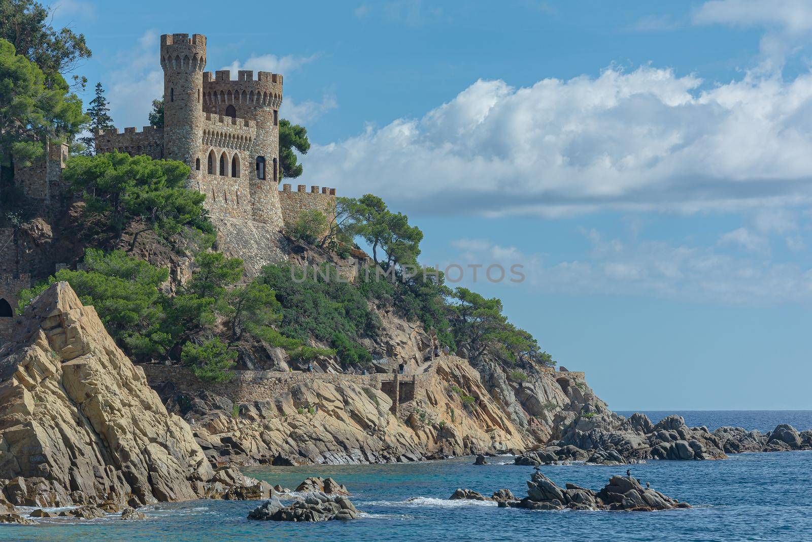 Lloret De Mar, Spain - 10/04/2019: Seascape. An old castle and a ship sailing away into the distance. Stock photo.