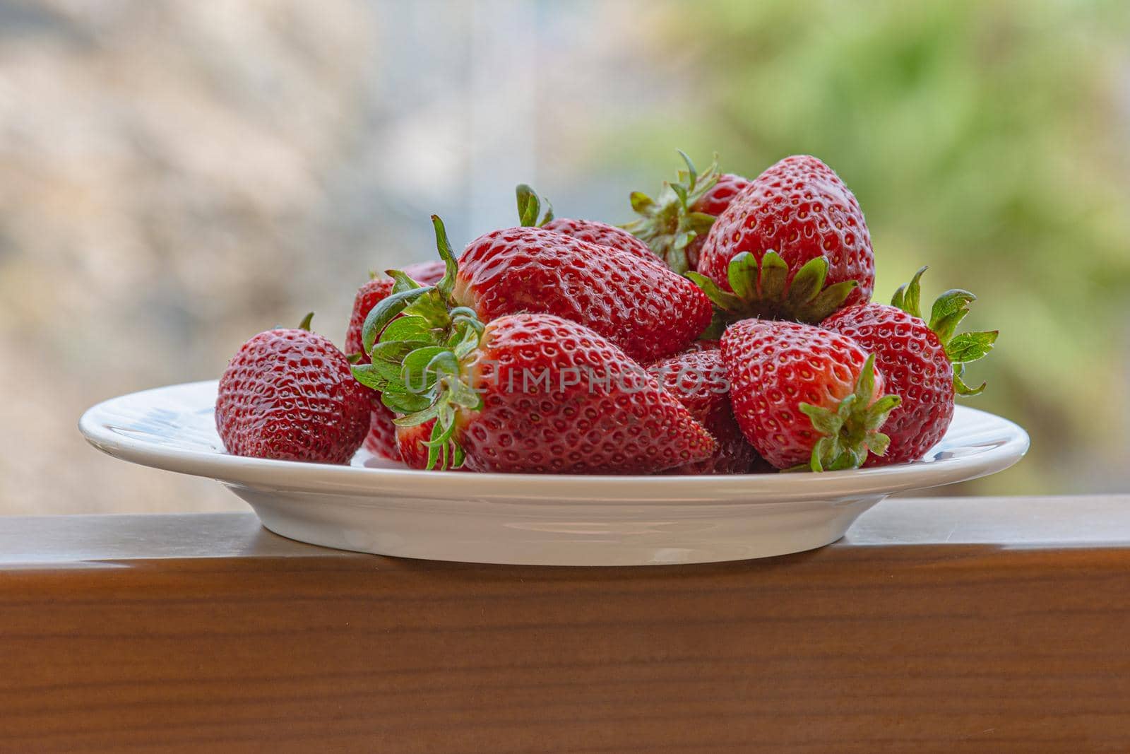 Red ripe strawberries on a plate. Blurry background, close-up. by Grommik