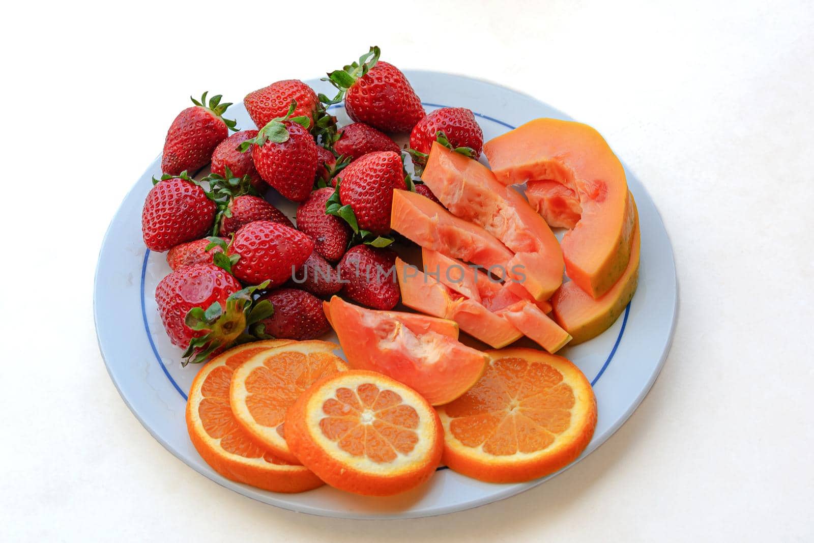 Fruit mix, strawberries, papaya and orange slices. Blurry background, close-up. Stock photo