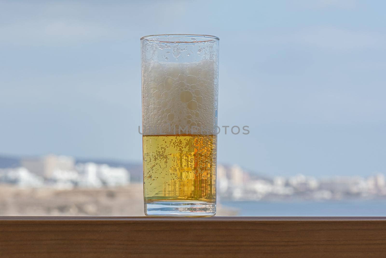 glass of light foamy beer in close-up on a blurry background. Stock photo
