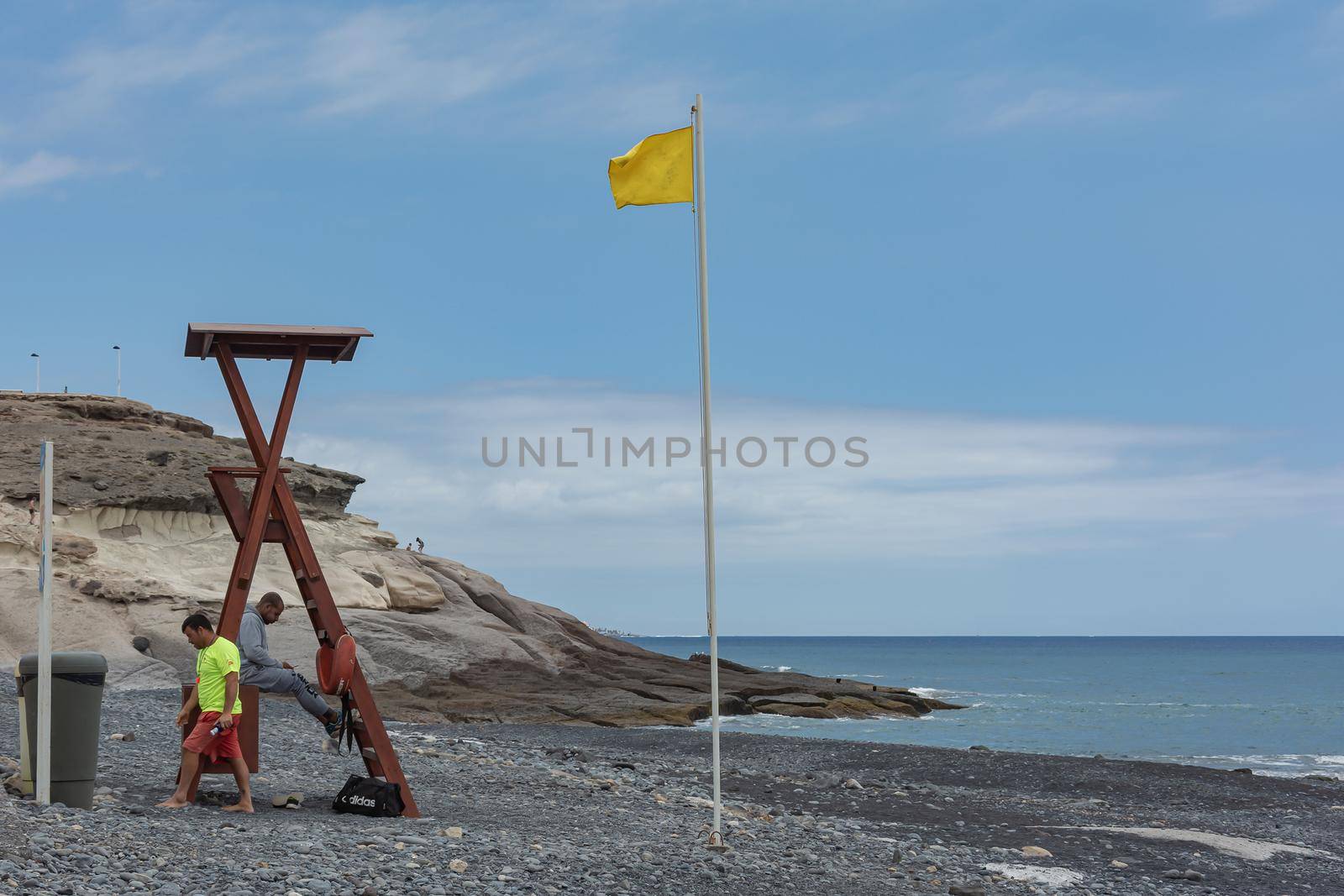 Tenerife, Spain - 05/10/2018: lifeguards on a deserted beach and a yellow flag by Grommik