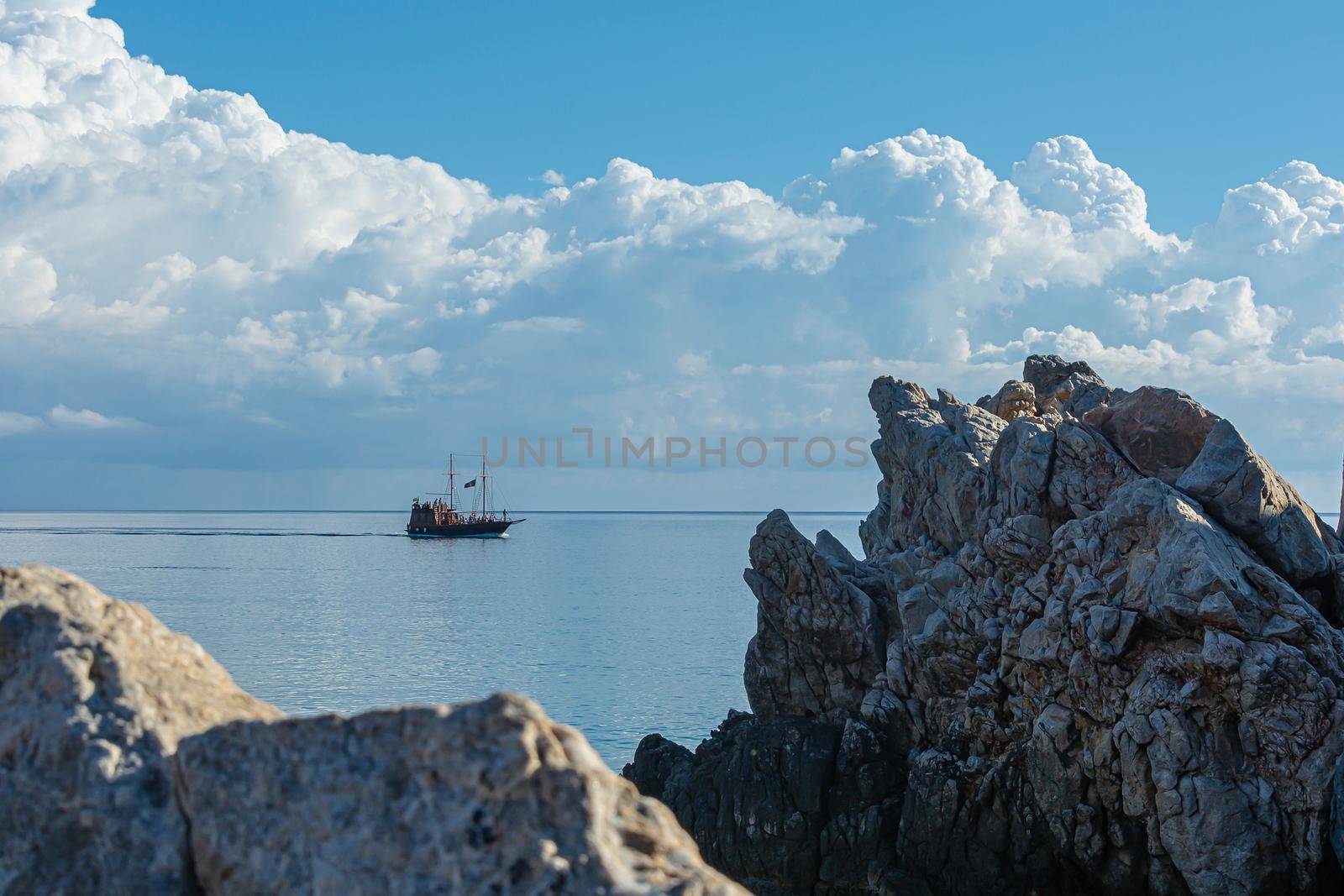 Greece, Crete-09/29/2015: Tourist boat on the background of the horizon and Cumulus clouds by Grommik