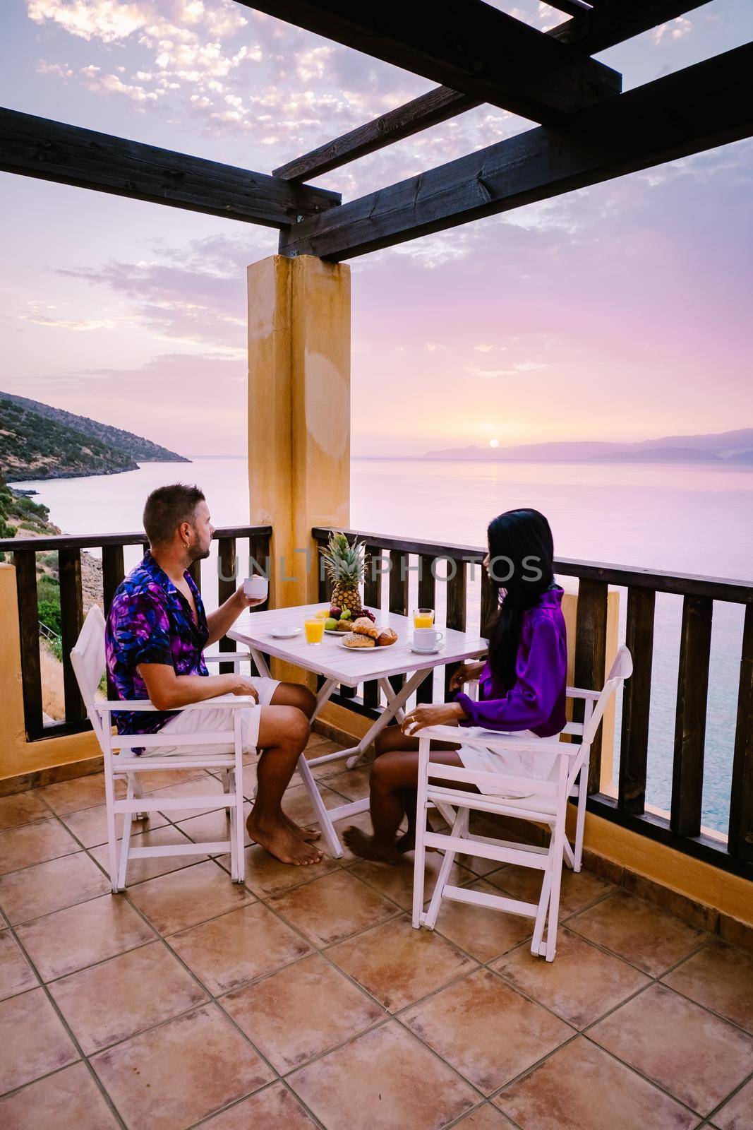 couple men and woman watching sunset over the ocean of Crete Greece by fokkebok