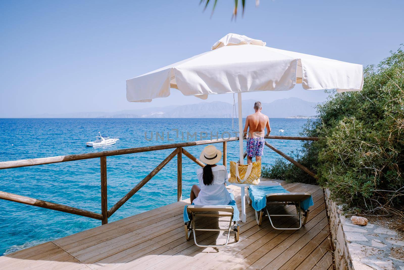 Couple in loungers on a tropical beach of Crete Greece. Europe