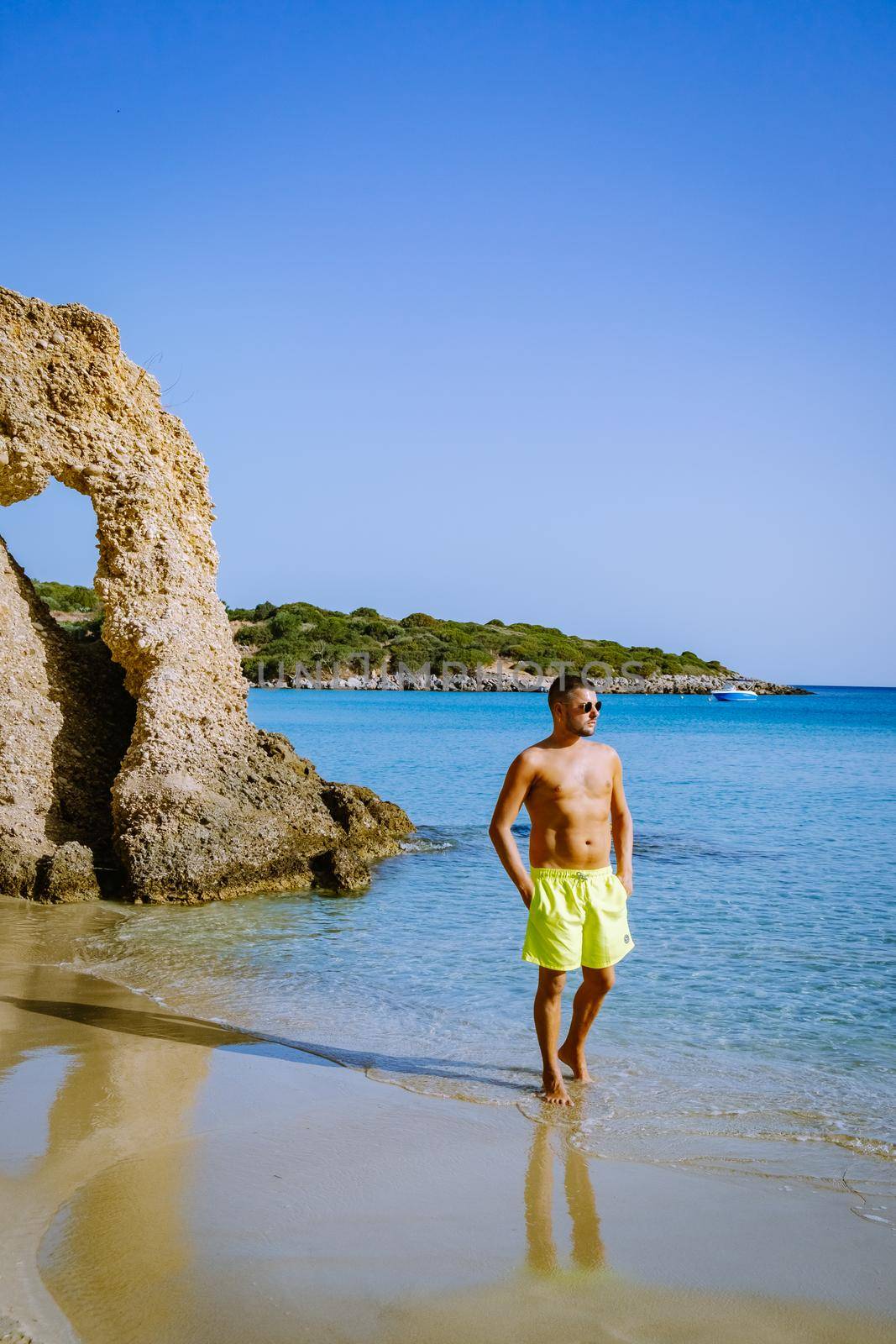 Tropical beach of Voulisma beach, Istron, Crete, Greece Europe, young guy in swim short on the beach