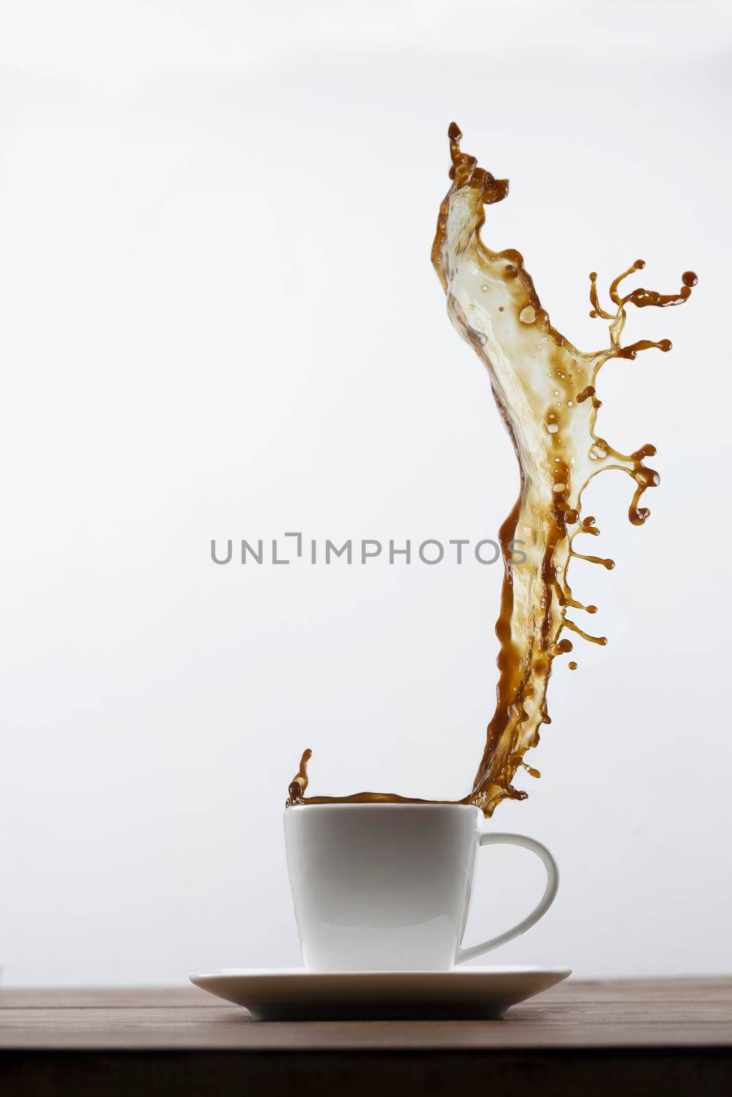 Splashing of coffee in white cup and falling coffee beans on white background by sashokddt
