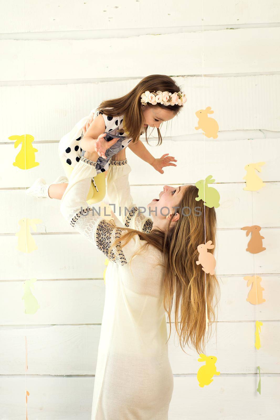 Happy mother with her daughter posing on white background with paper rabbit's shape. Easter holidays.