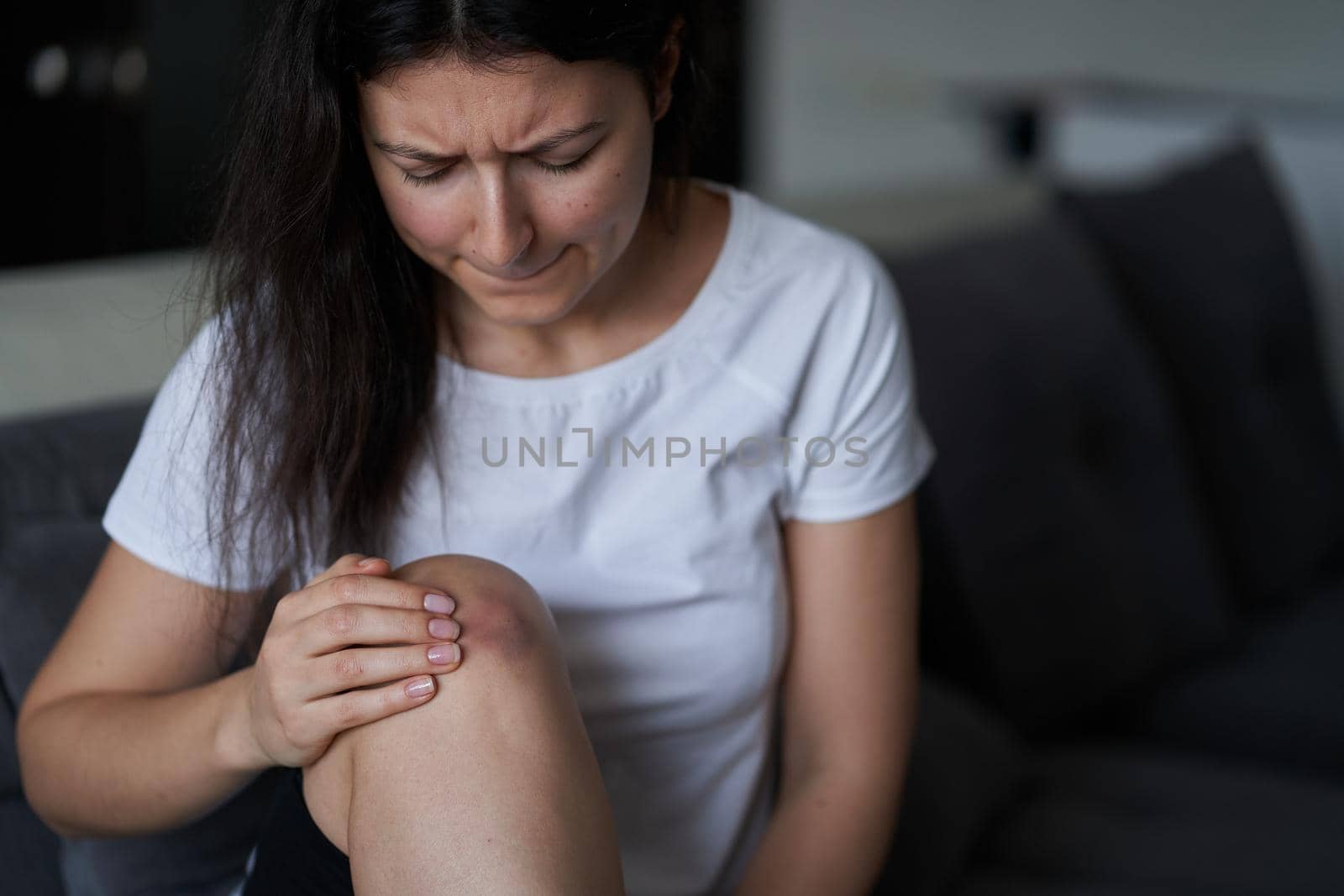 Close-up of a person massaging an injured knee joint. Bruise on the knee. Leg pain.