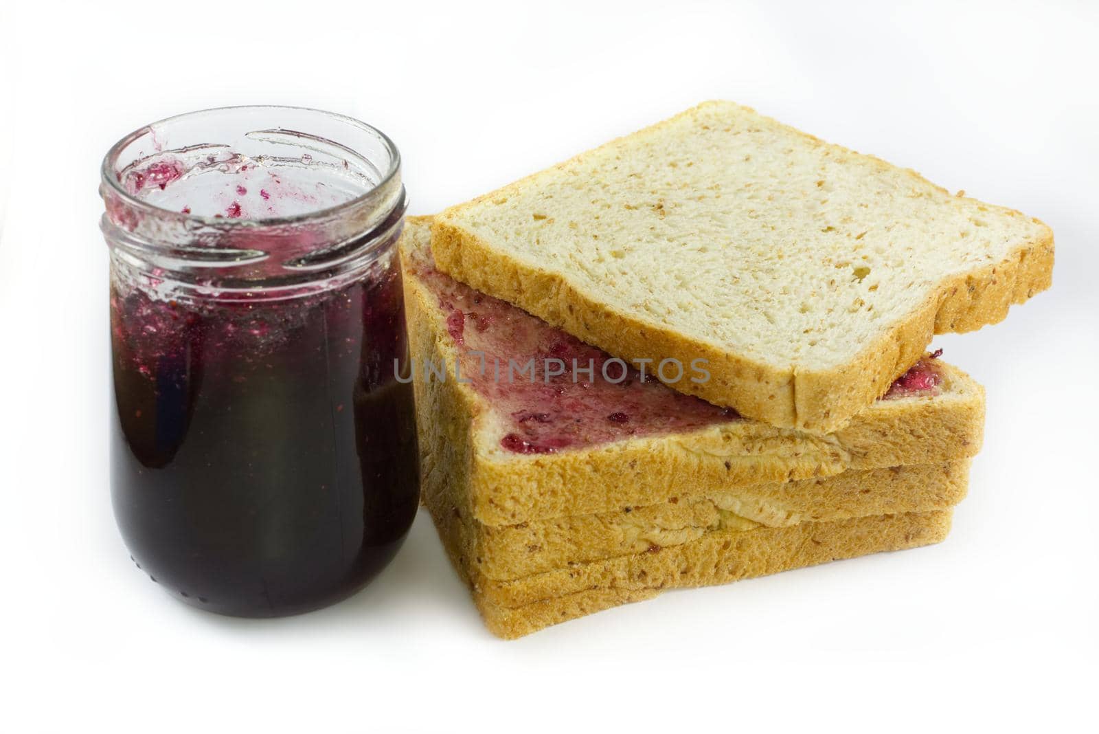 Whole wheat bread stack with grape jam on isolated white background.