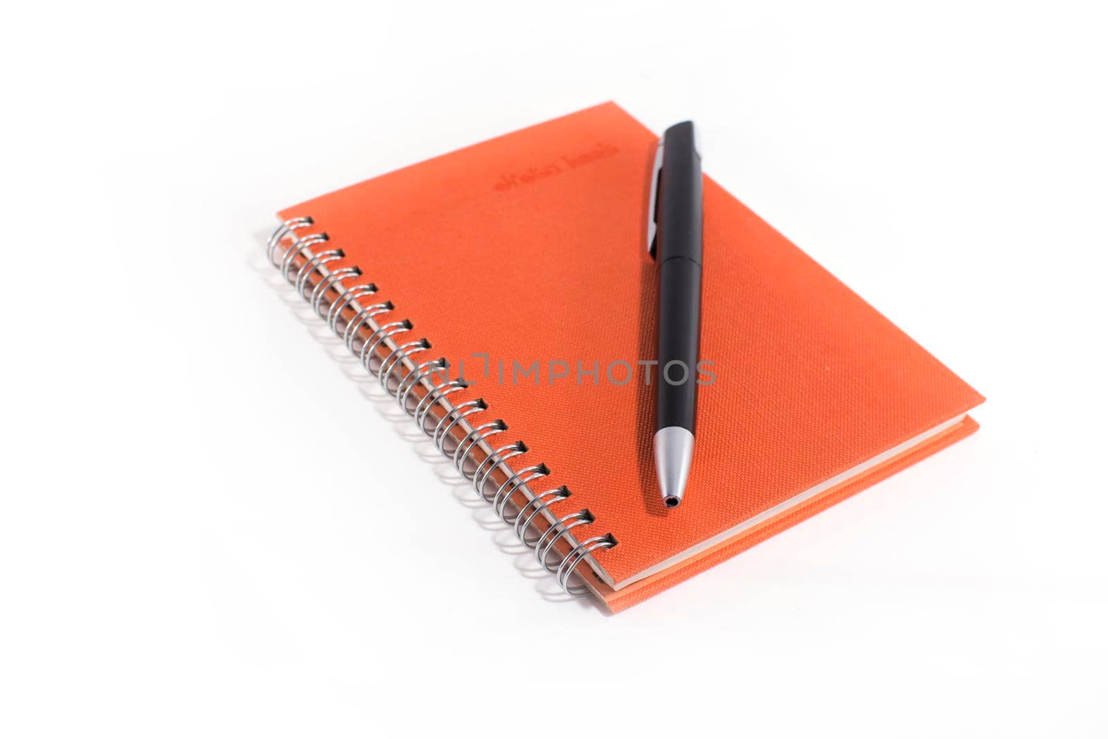 Orange notebook with black pen on white background.
