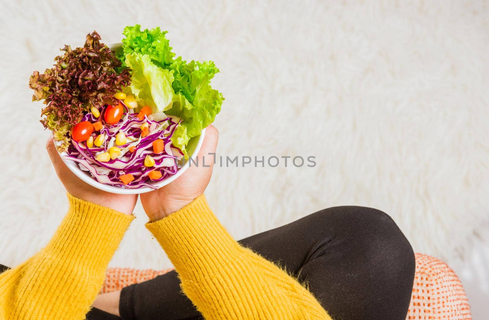 female hands holding bowl with green lettuce salad on legs by Sorapop