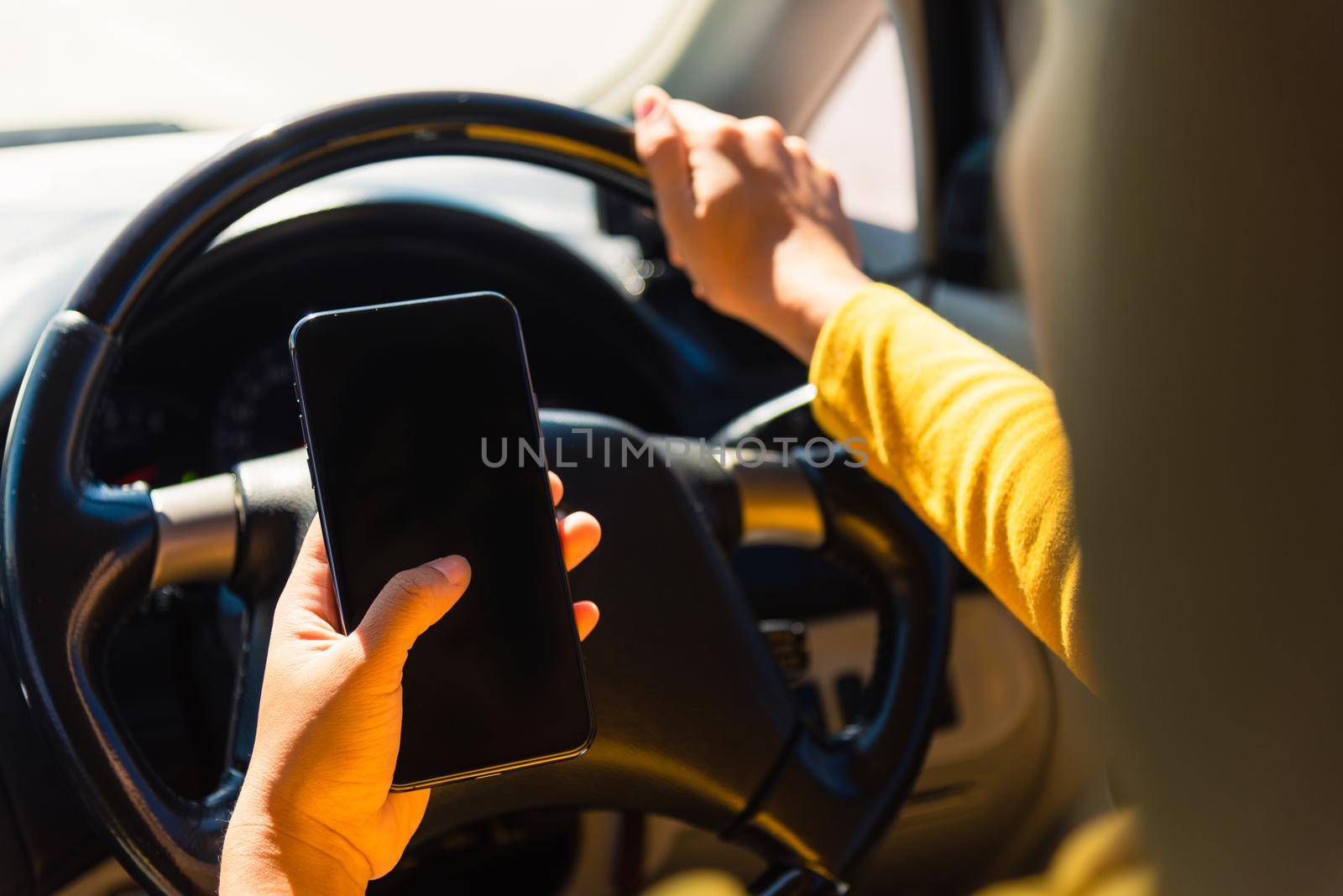 Asian woman inside a car and using a hand holding mobile smartphone blank screen while driving the car in the morning during going to work on highway, Transportation and vehicle concept