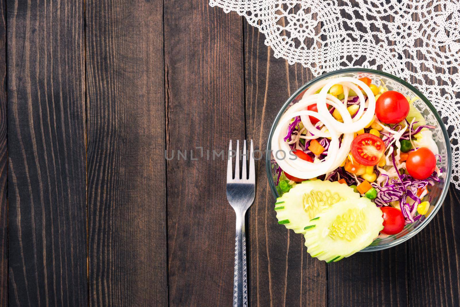 Top view of the healthy colorful fresh salad bowl with quinoa, tomatoes, and mixed greens vegetable in a dish on black wooden background, Health snack food