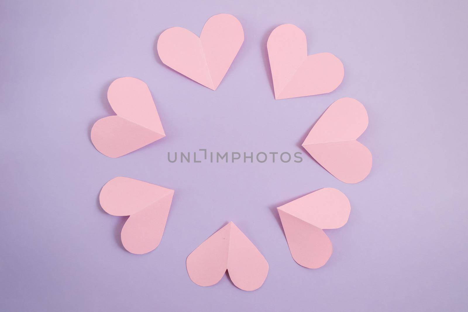Valentine's day background. Pink hearts laid out in a circle on a pastel purple background. Valentine's day concept. Layout for postcards and congratulations. Flat lay, top view, copy space