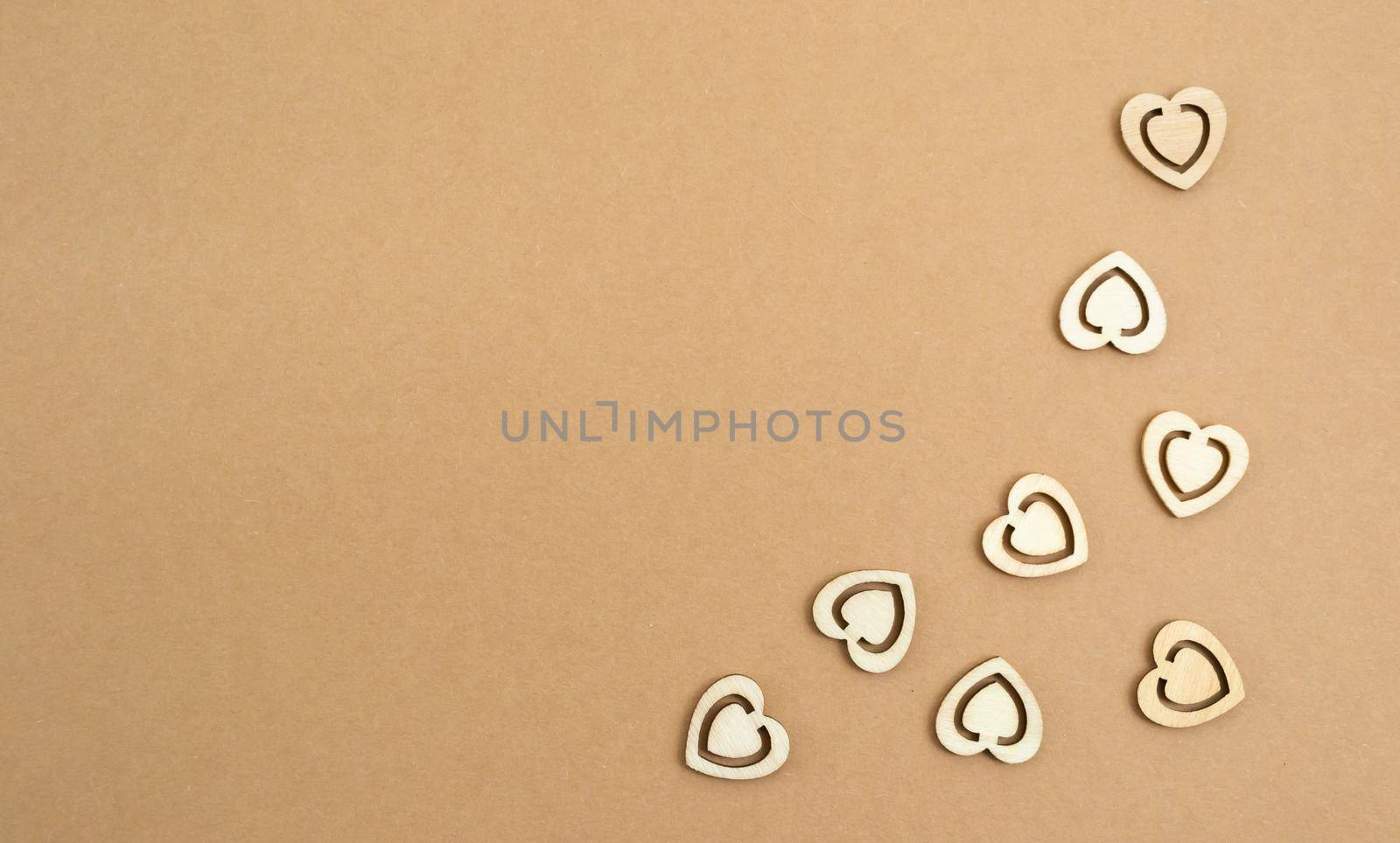 Wooden hearts on a pastel craft paper background. Abstract background with wood cut shapes. Sainte Valentine, mother's day, birthday greeting cards, invitations. Copy space.