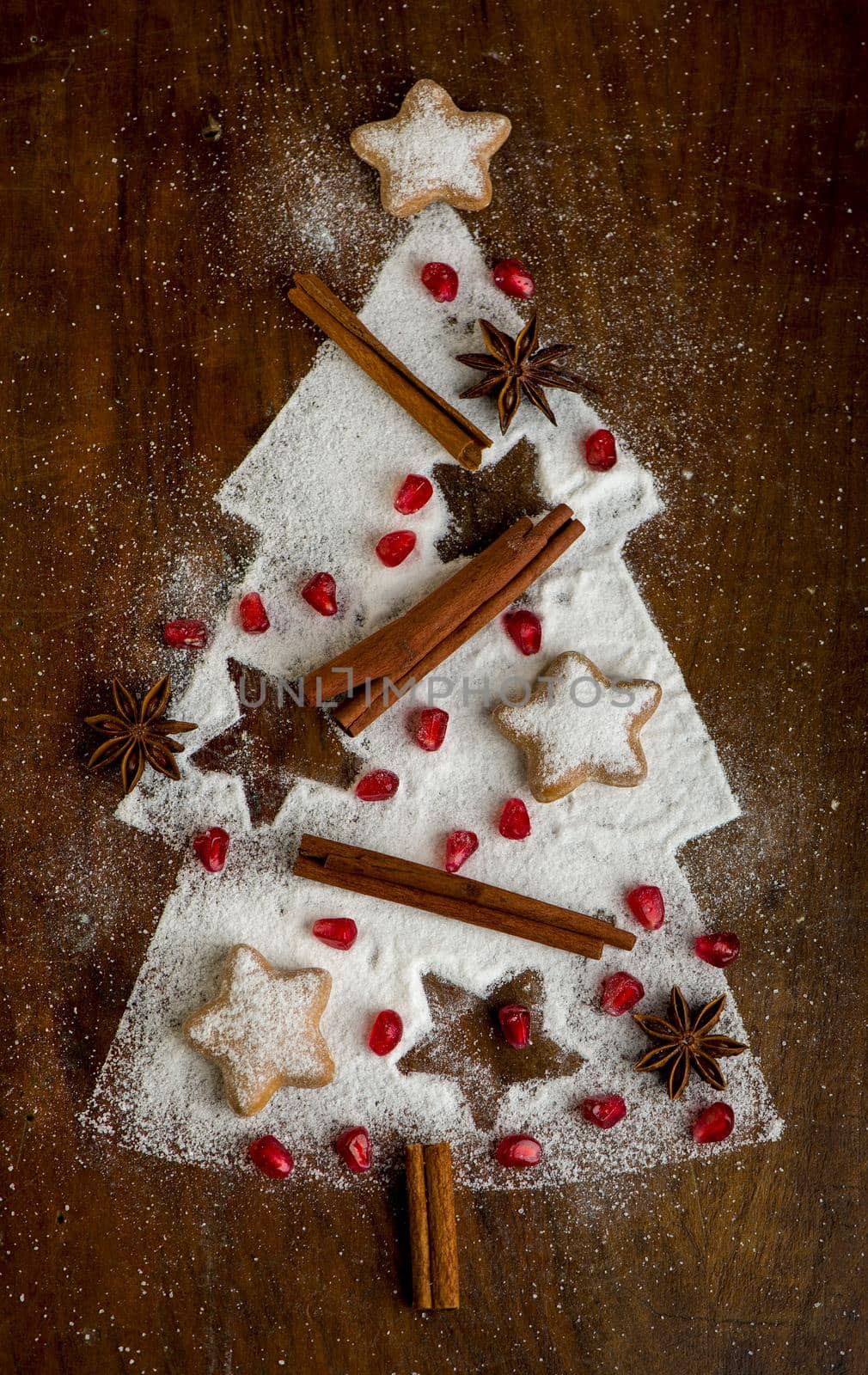 Homemade cookies folded in the form of a Christmas tree with cinnamon on a baking sheet with powdered sugar, top view