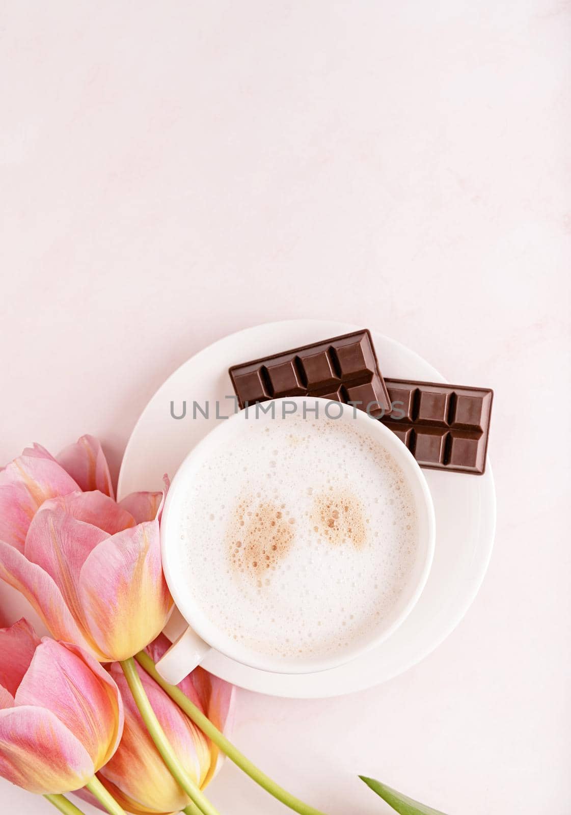 Cup of cappuccino and pink tulips top view on marble background