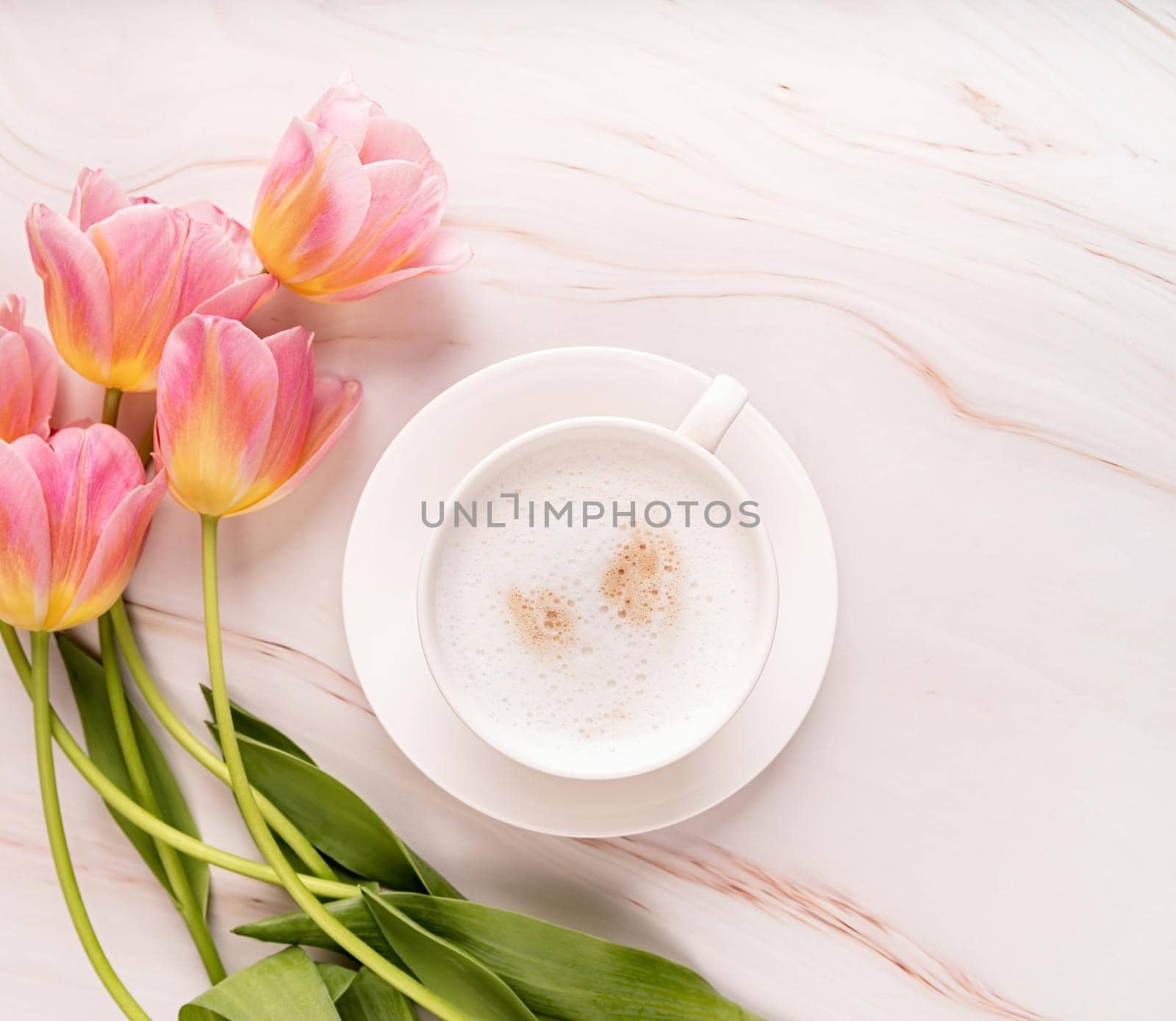 Cup of coffee and pink tulips top view on marble background by Desperada